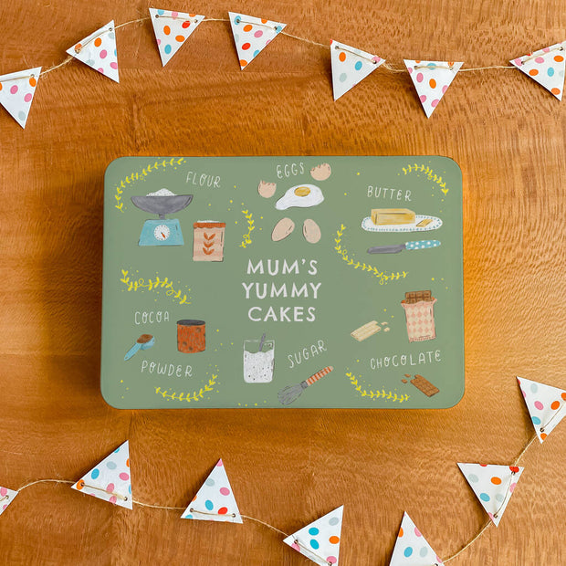 Sage green illustrated baking design tin with personalised message on a wooden background with bunting photo prop